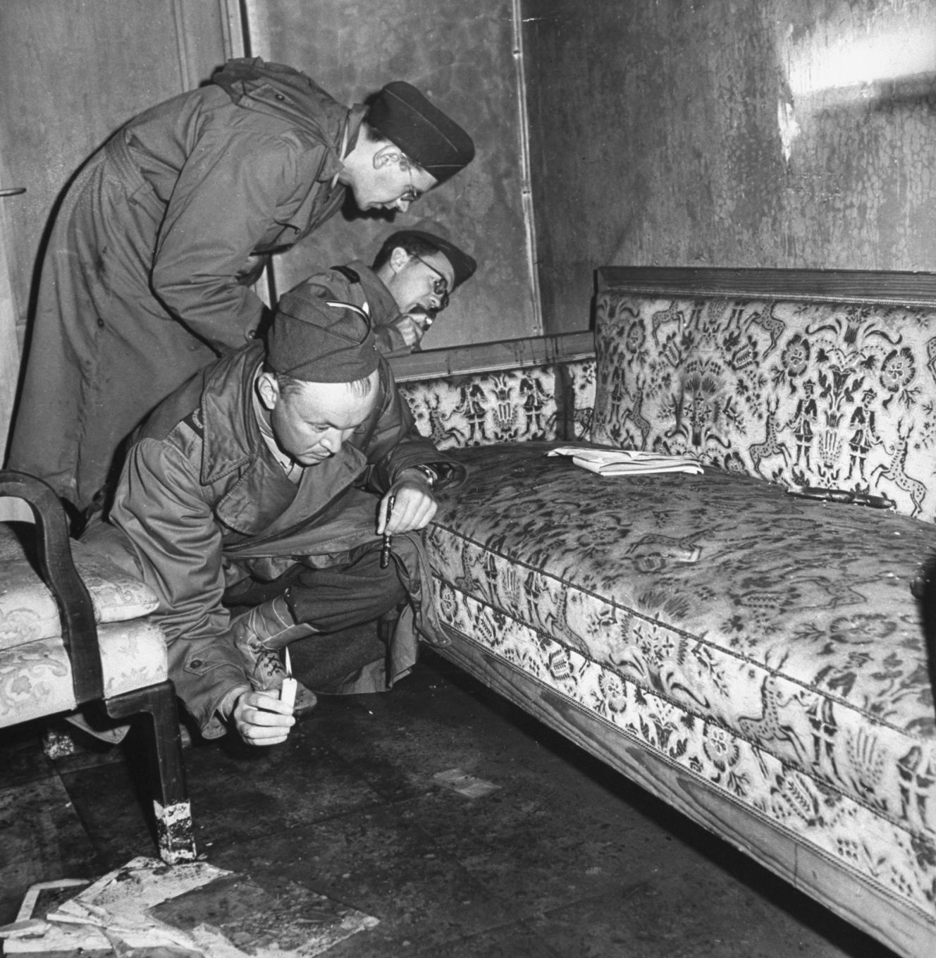 Allied soldiers examining the sofa associated with Adolf Hitler's death in the Berlin bunker